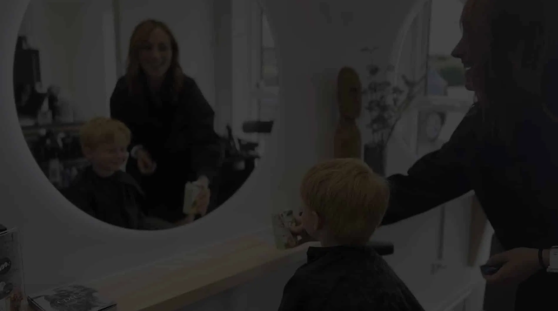 Christina klipper en dreng foran spejlet i salonen